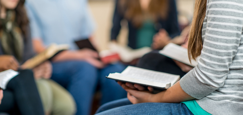 A group of high school students studying the Bible together.